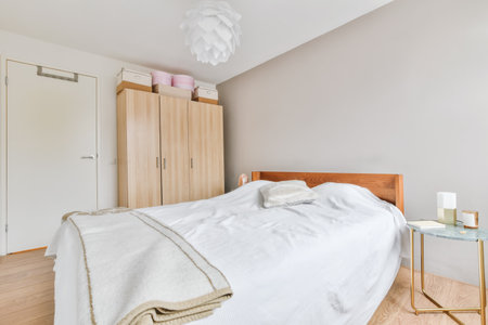 An interior shot of a bedroom with a wardrobe in white walls and a wooden floor