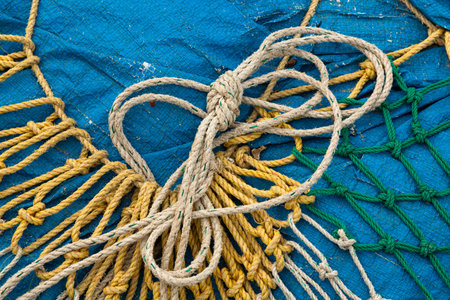 Various fishing nets lying on a blue plastic tarp on the beach of Kerala