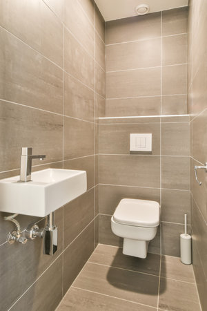 A vertical shot of a bathroom with brown tiles on the wallの写真素材