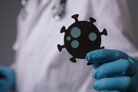 A doctor with gloves holding a virus made with paperの写真素材