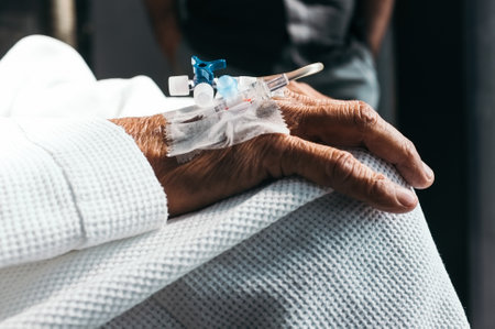 A closeup shot of an old man's injected hand with a syringe attached, with a man in the backgroundの写真素材