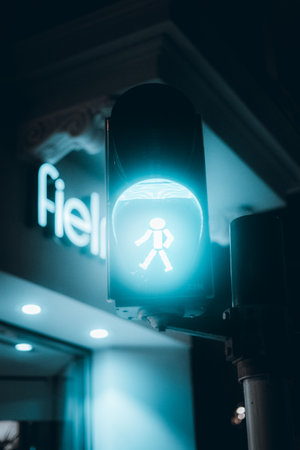An urban view of blue neon pedestrian passing traffic light on the road at nightの写真素材