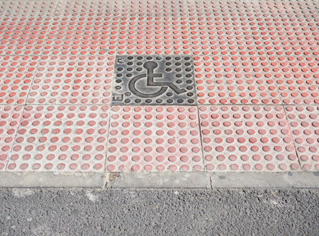 A closeup of red paving with a gray tile sign of wheelchairの写真素材