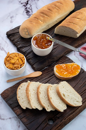A vertical shot of a breakfast board with sliced bread and jam