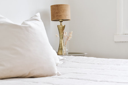 A comfortable bed and stylish lamp in the light bedroomの写真素材