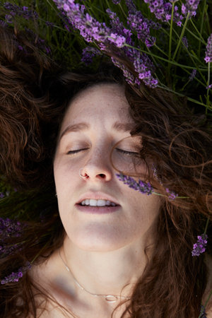 A vertical closeup of a beautiful young woman in the lavender field.の写真素材