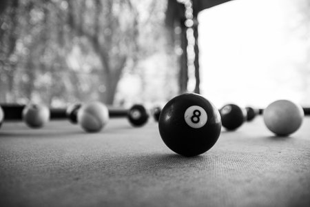 A grayscale shot of billiard balls on the table with a blurry background