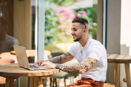 A young Caucasian male working with a laptop from an outdoor cafeの写真素材