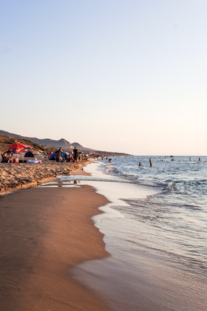 A vertical shot of people at the beach under a clear skyの写真素材
