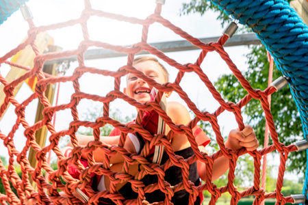 A child playing in a park playground wearing red t-shirt on a  bright sunny dayの写真素材