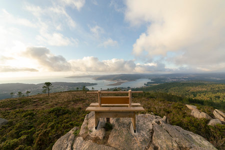 A wooden bench on the top of a rock with a beautiful nature viewの写真素材