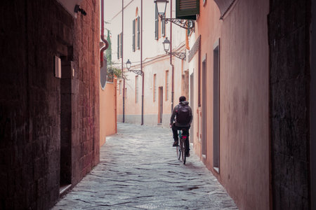 A man riding a bike in a narrow streetの写真素材