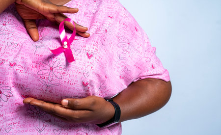 A black female doctor with the breast cancer awareness symbol on her uniform