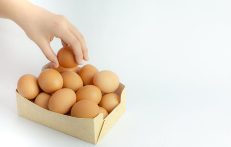 A box of frsh eggs isolated on a white background and a hand holding itの写真素材