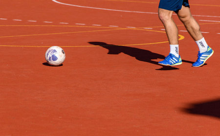 A male athlete playing soccer in a sunny red courtの写真素材