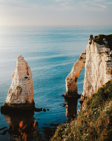 A Mesmerizing view of location gite Etretat, France in the blue water under a blue cloudy skyの写真素材
