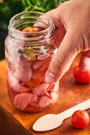 A closeup shot of putting pickles in a jar at a table in the kitchenの写真素材