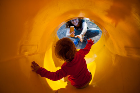 A cute Caucasian toddler sliding on a slide in a playgroundの写真素材