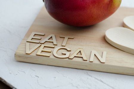 An eat vegan text on a wooden surface with red fruit in a kitcheの写真素材