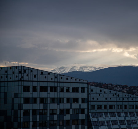 A beautiful shot of a building with a mountain in the background under the cloudy skiesの写真素材