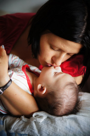 A young Caucasian mother kissing her sleeping babyの写真素材
