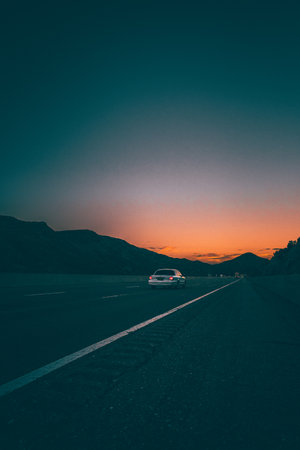 A car driving through an asphalt road with a scenic sunset horizonの写真素材