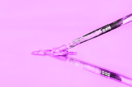 A closeup of a used paint brush with pink paint on the mirrorの写真素材