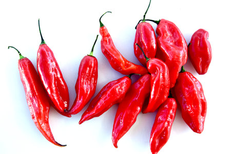 A high angle shot of a group of red small spicy peppers on a white background