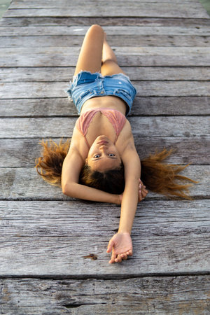 An attractive sexy Indonesian woman lying on wooden plank in Sulawesi, Togian Islandsの写真素材