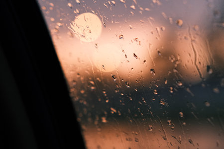 A window with some raindrops and bokeh lights background