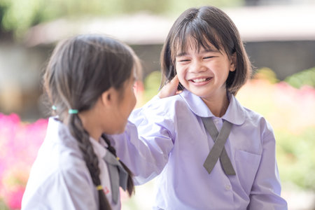 A shallow focus of two adorable kids in the school uniform playing outdoors on a sunny dayの写真素材