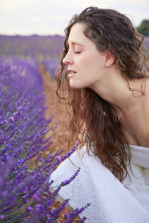 A vertical closeup of a beautiful young woman in the lavender field.の写真素材