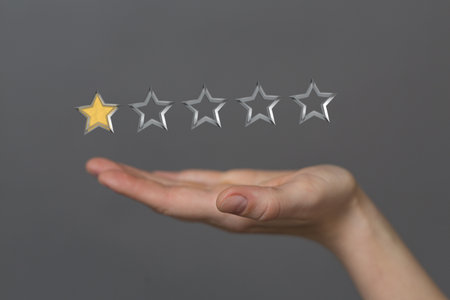 A male's hand holding illustrated review star on a grey backgroundの写真素材
