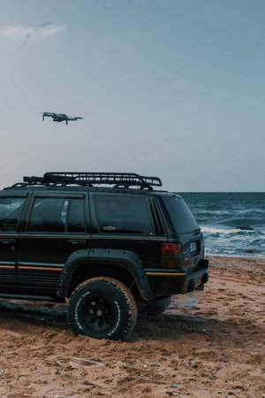 A drone flying over an offroad vehicle on the beachの写真素材