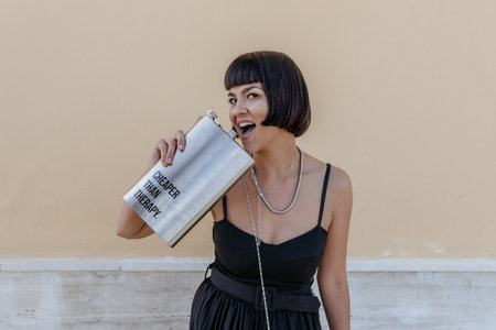 Attractive young woman with beautiful black hair, holding large silver flask with text cheaper than...