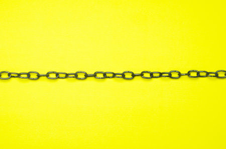 A closeup shot of a small metal chain link isolated on a yellow backgroundの写真素材