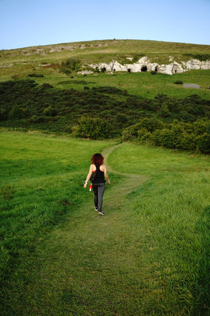 A vertical shot of a female hiking on the forested hillの写真素材