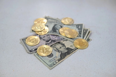 A closeup of bitcoins and dollar banknotes on a white backgroundの写真素材