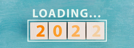 2022 is standing in orange colored letters on wooden cubes, the word loading is standing aboveの写真素材