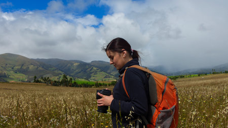 A female hiker taking a picture with a camera in a picturesque valleyの写真素材