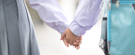 A closeup of kids holding hands outdoors with a blurry backgroundの写真素材