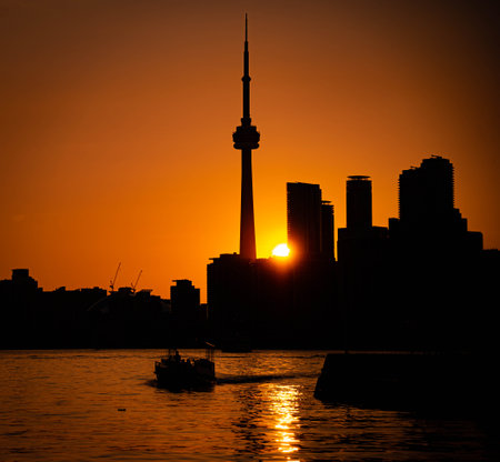 The silhouette of the CN Tower surrounded by water and buildings during a beautiful sunset in Toronto, Canadaの写真素材