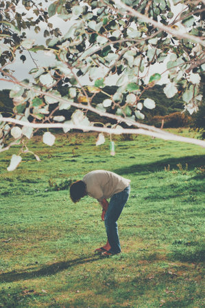 A vertical shot of a bent down person in a garden on a sunny daの写真素材