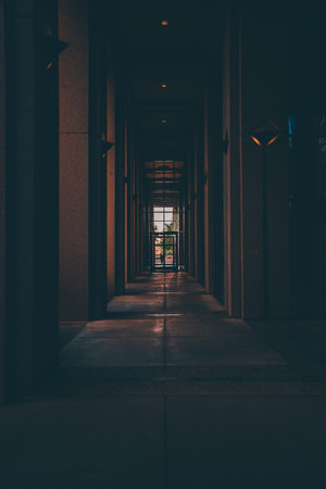 An empty corridor of a building leading to a glass doorの写真素材