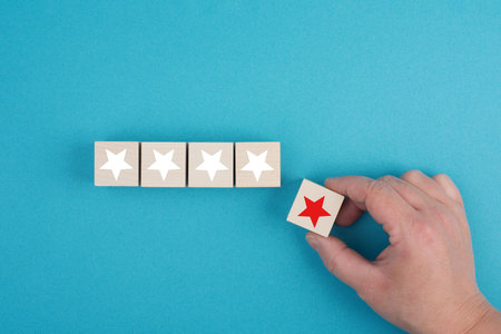 Wooden cubes with white stars, one block with a red star holding in the handの写真素材