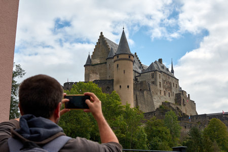 A Hispanic man taking photos of Vianden Castle in Luxembourgの写真素材