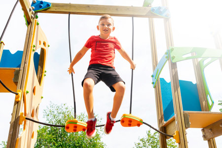 A child playing in a park playground wearing red t-shirt on a  bright sunny dayの写真素材