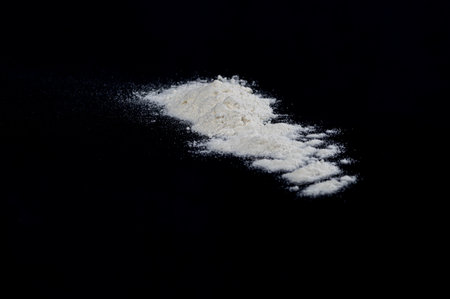 A close-up shot of a pile of white wheat flour isolated on a black backgroundの写真素材