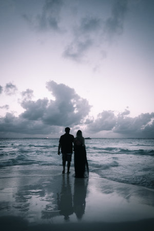 A couple enjoying the sight of the sea on the beachの写真素材