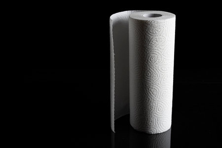 A closeup of a kitchen paper towel roll isolated on a black backgroundの写真素材